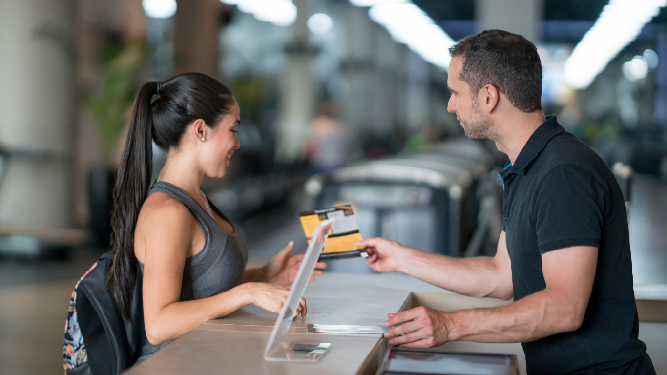 Woman at the gym talking to receptionist about membership plans