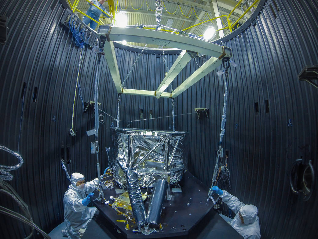 guys in bunny suits work on equipment in a chamber