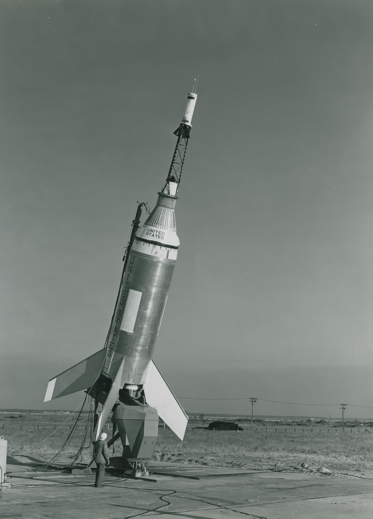 Black and white photo of a rocket horizontal be prepared for launch.