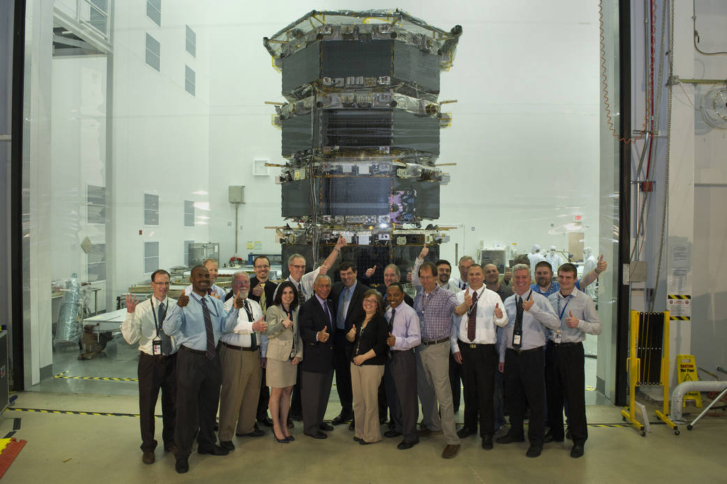 Charles Bolder and other NASA senior staff pose in front of the stacked MMS spacecraft with MMS personnel.