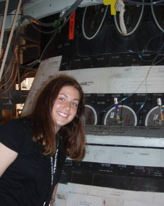 A young woman stands next to the Space Shuttle during her internship at NASA