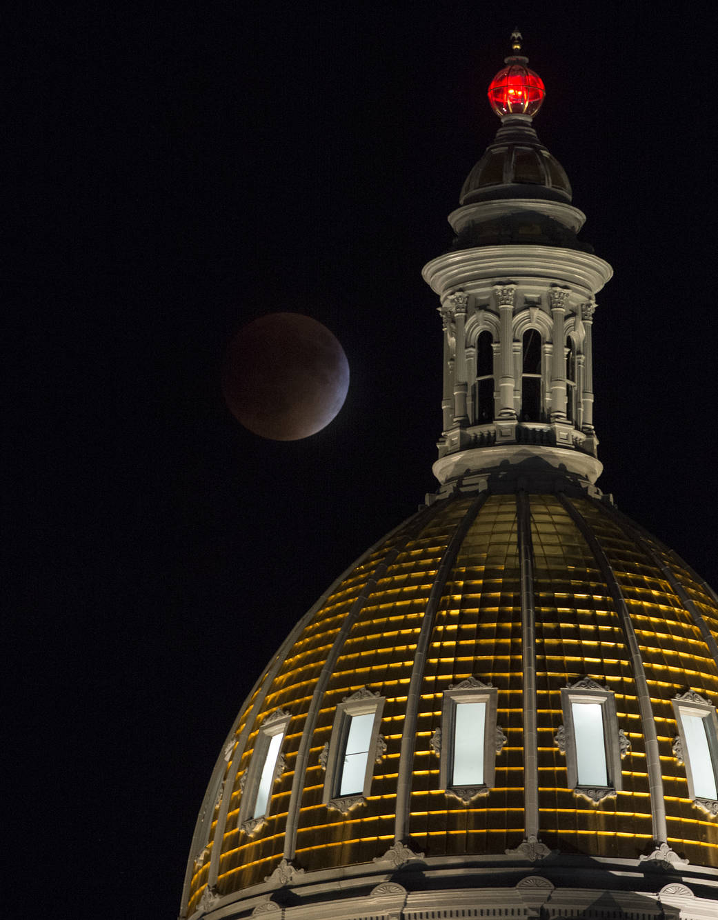 A perigee full moon, or supermoon, is seen during a total lunar eclipse behind the Colorado State Capitol Building
