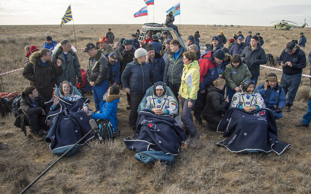 Expedition 49 crew members in chairs outside Soyuz