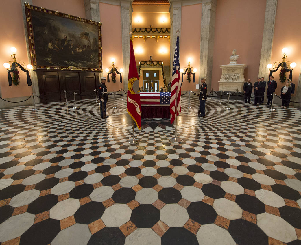 Flag draped coffin inside statehouse with guards