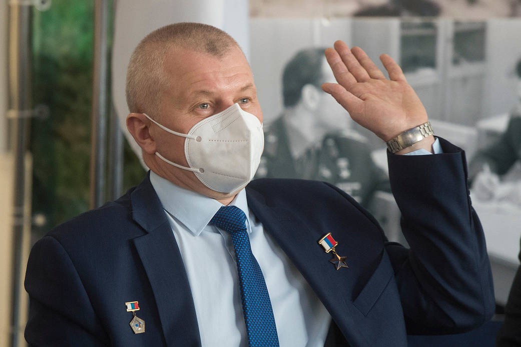 Cosmonaut Oleg Novitskiy waves during a press conference