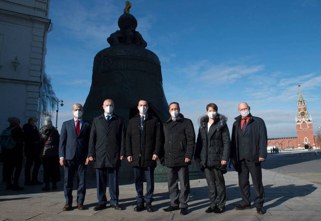 Expedition 65 prime crew members pose for a photo in front of the Tsar Bell
