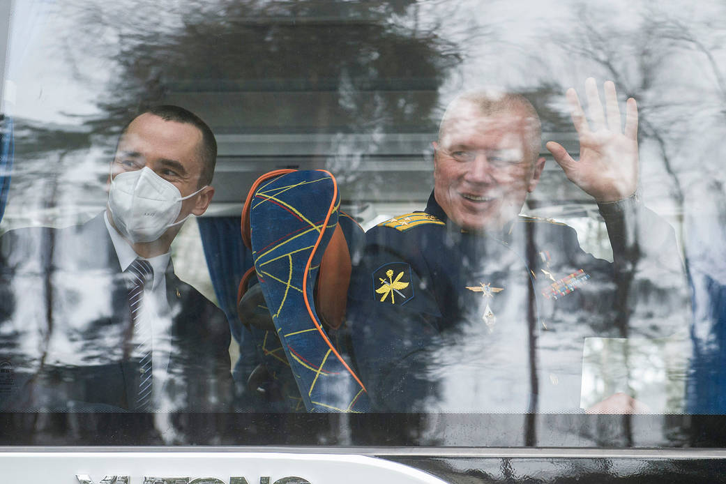 Expedition 65 prime crew members wave goodbye after boarding the bus