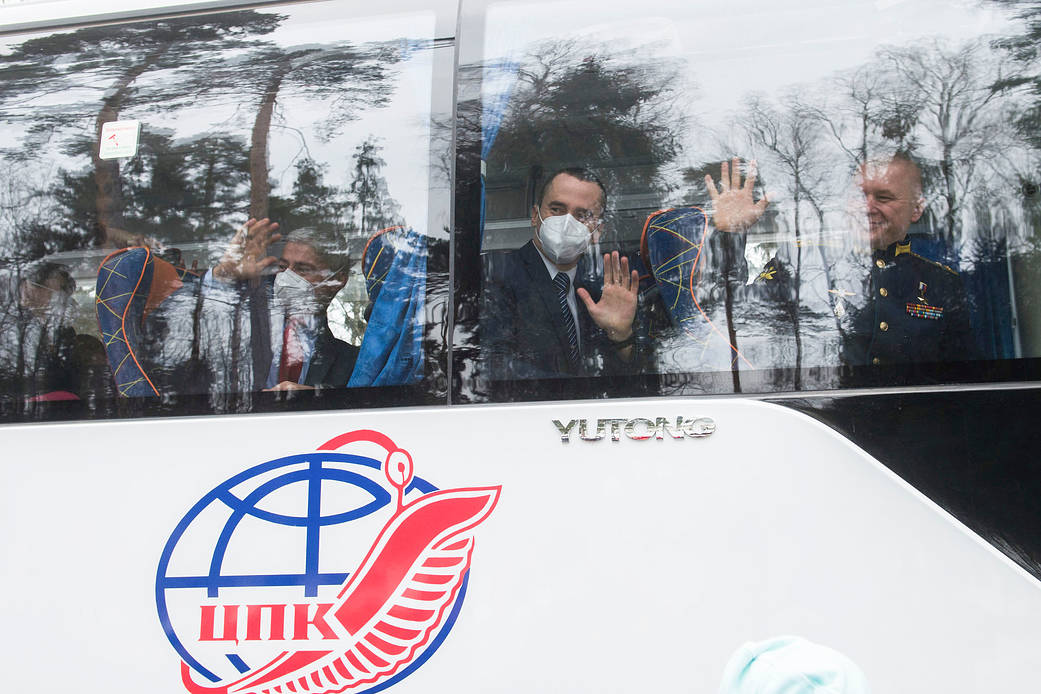 Expedition 65 prime crew members wave goodbye after boarding the bus