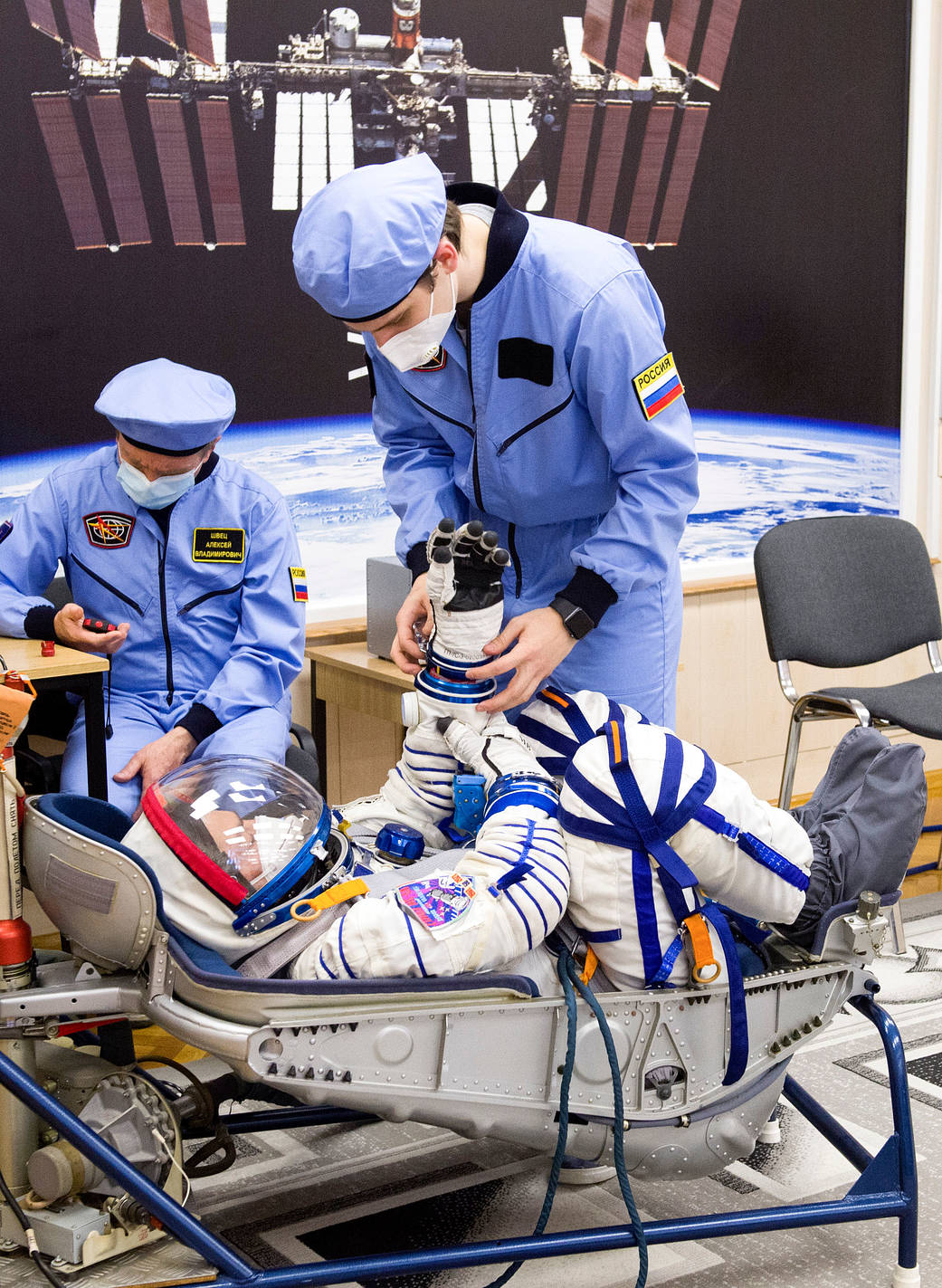 Mark Vande Hei of NASA is assisted with his glove during suit check