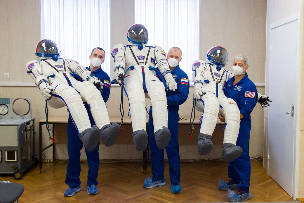 Expedition 65 prime crew members holding their Sokol suits