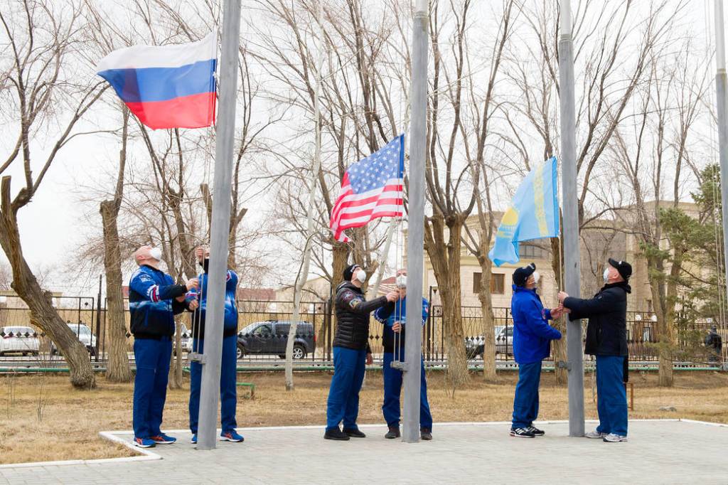 Expedition 65 prime and backup crew members raise the flags