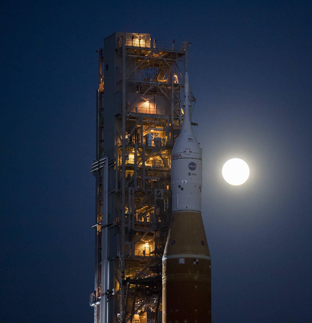 The Moon rises behind NASA's Space Launch System rocket and Orion spacecraft. 