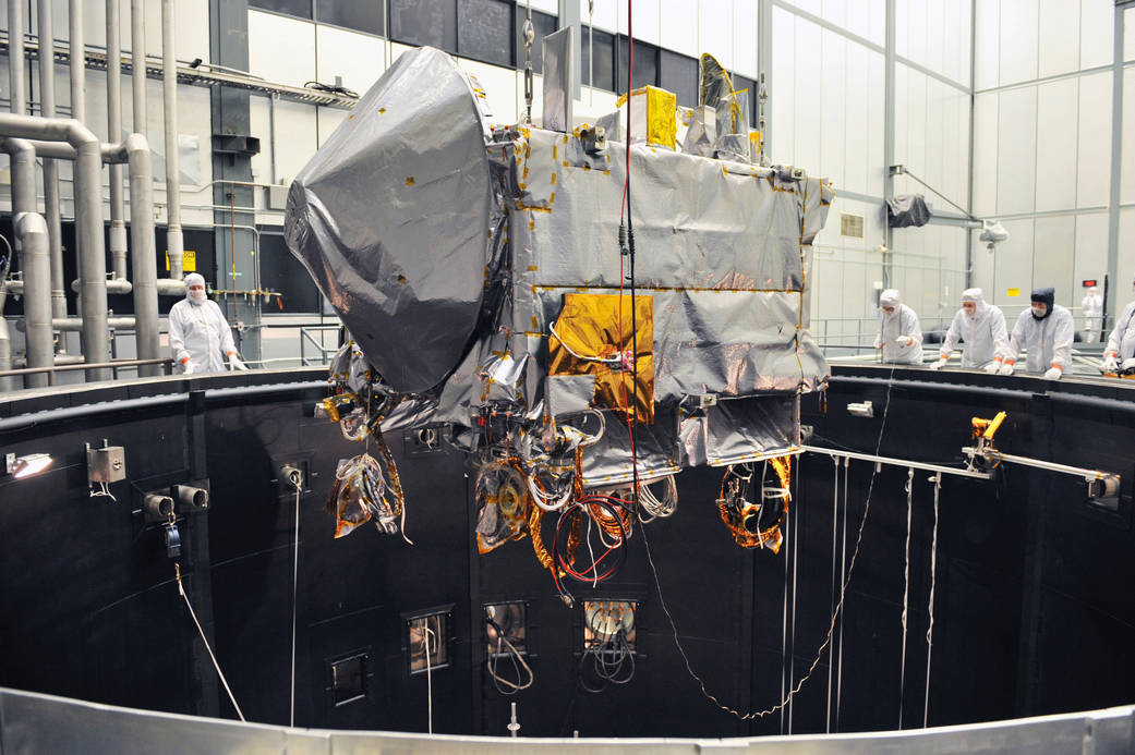 silvery spacecraft being lowered into dark chamber