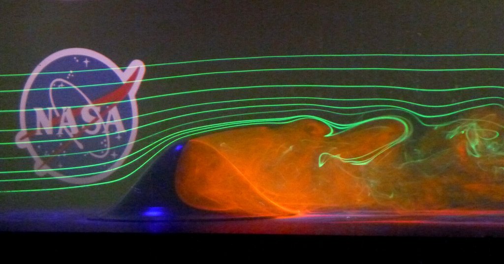axisymmetric hill surrounded by lasers and smoke. NASA logo in background.