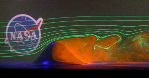axisymmetric hill surrounded by lasers and smoke. NASA logo in background.