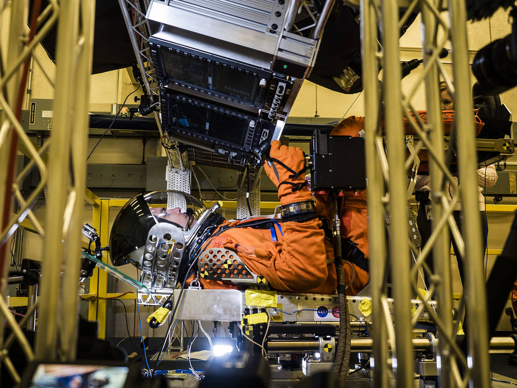 Test subject in crew escape suit seated inside test module