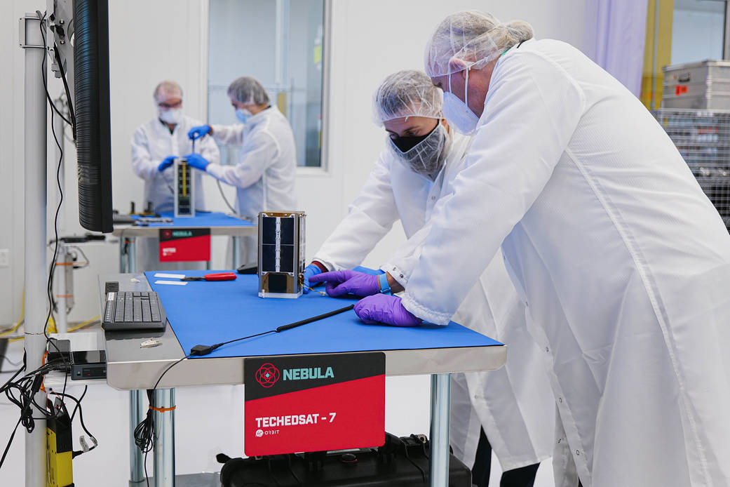 NASA engineers Marcus Murbach and Hunter Kanniainen prepare the TechEdSat-7 CubeSat for flight.