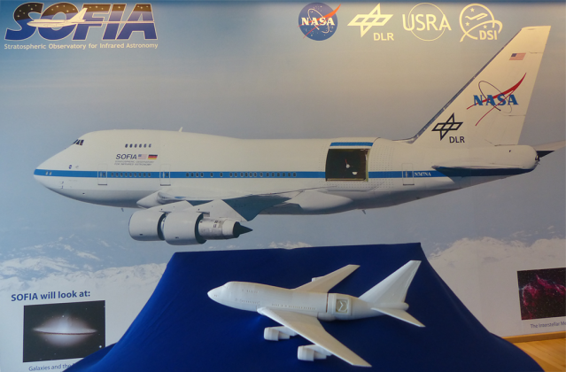 A SOFIA 3D printed model in front of a a photo of the aircraft. 
