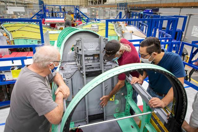 Technicians examining the cockpit section of NASA’s X-59 plane.