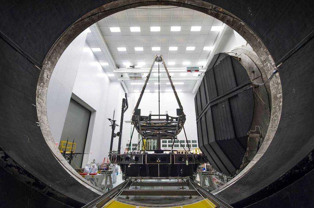 A tall instrument in a white room seen through a dark hole