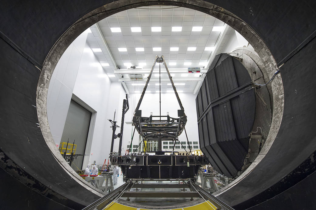 A tall instrument in a white room seen through a dark hole