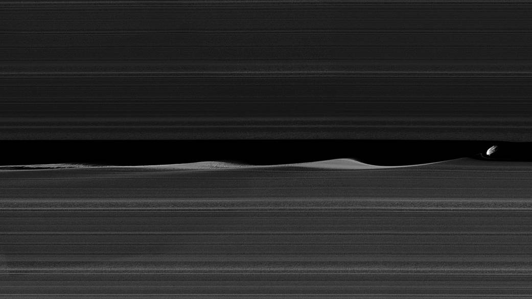 Daphnis, one of Saturn's ring-embedded moons, is featured this view, kicking up waves as it orbits within the Keeler gap