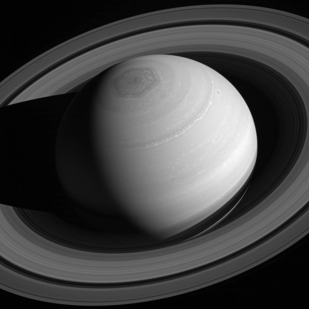 A grayscale photo of Saturn and its rings taken from overhead by the Cassini spacecraft. 