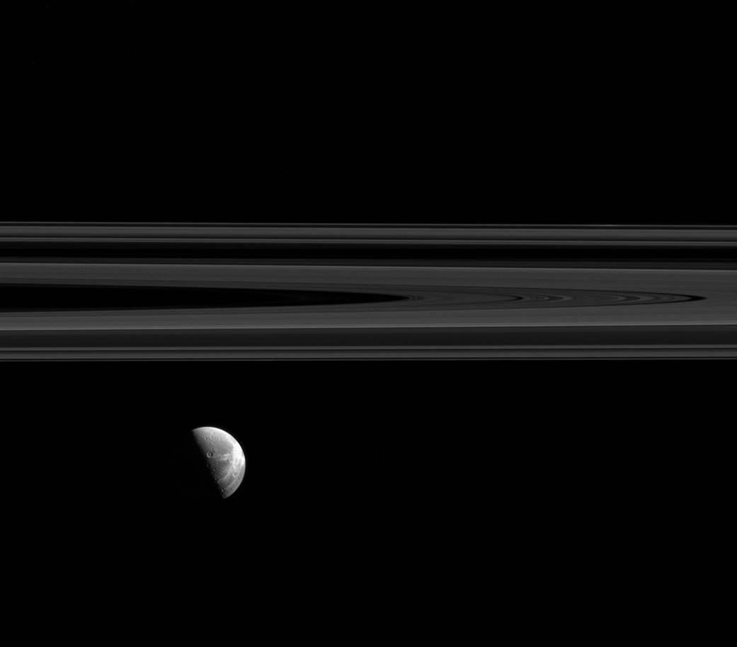 Dione's beautiful wispy terrain is brightly lit alongside Saturn's elegant rings