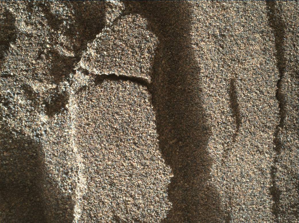 This view shows grains of sand where NASA's Curiosity Mars rover was driven into a shallow sand sheet near a large dune