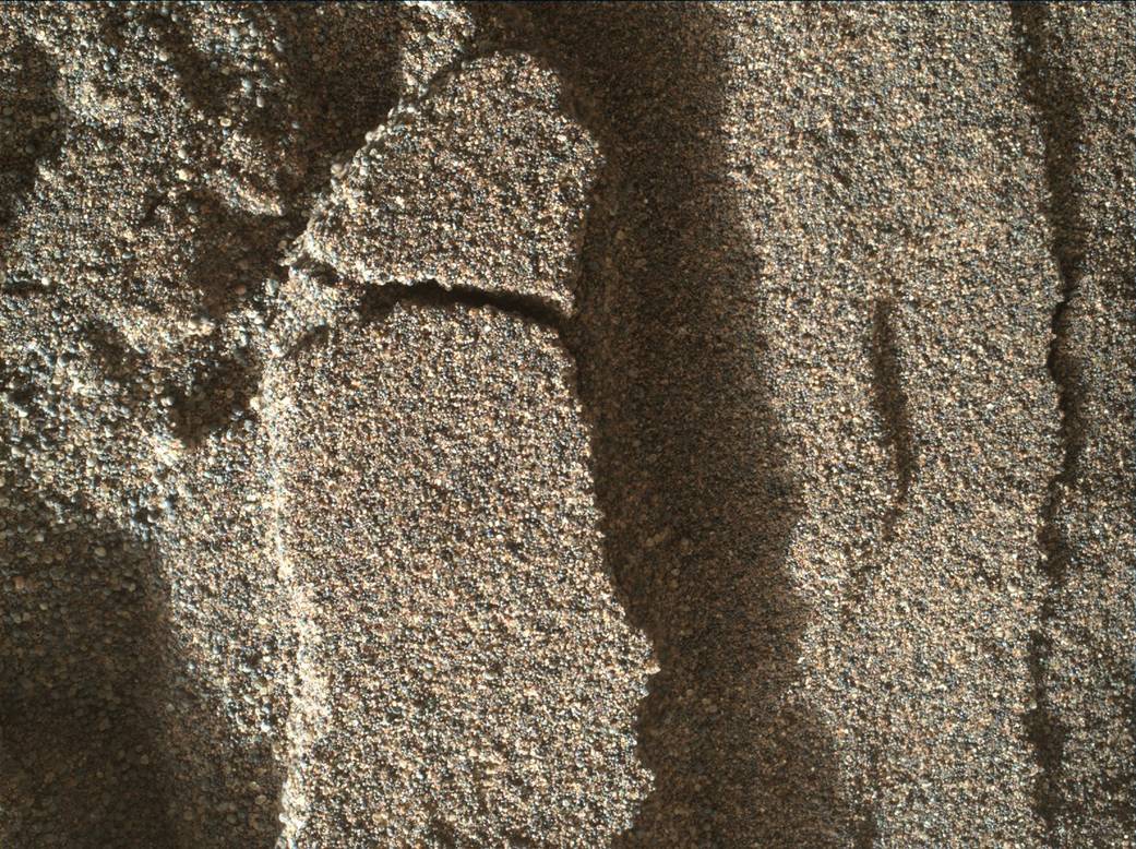 This view shows grains of sand where NASA's Curiosity Mars rover was driven into a shallow sand sheet near a large dune