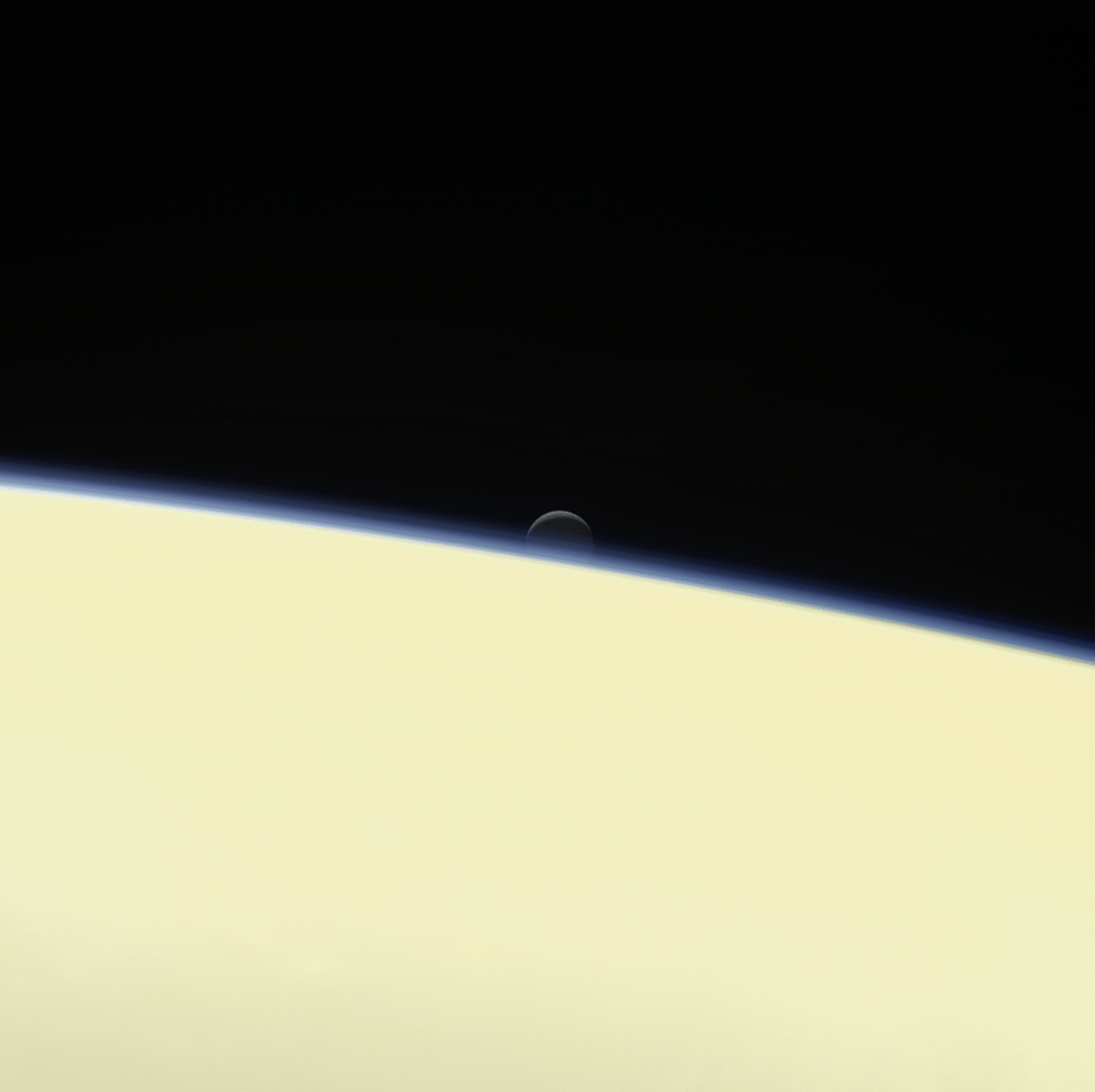 moon Enceladus behind Saturn