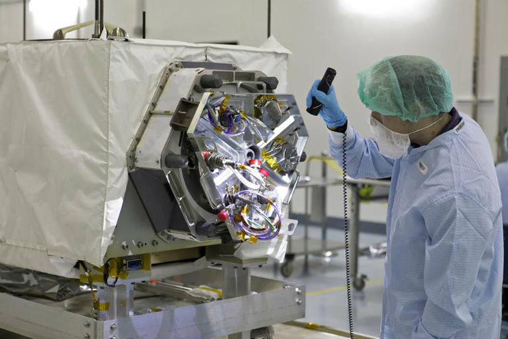 A technician inspects NASA's ECOSTRESS instrument in a clean room at Kennedy Space Center in Florida