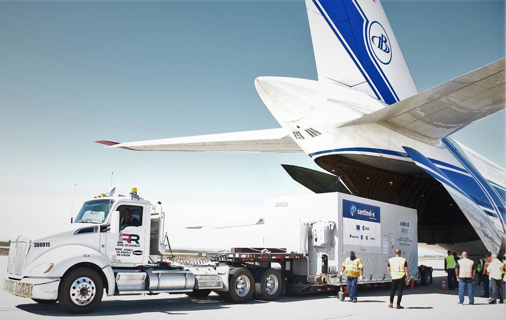 A shipping container containing the Sentinel-6 Michael Freilich satellite is transported on a truck to the SpaceX payload proces