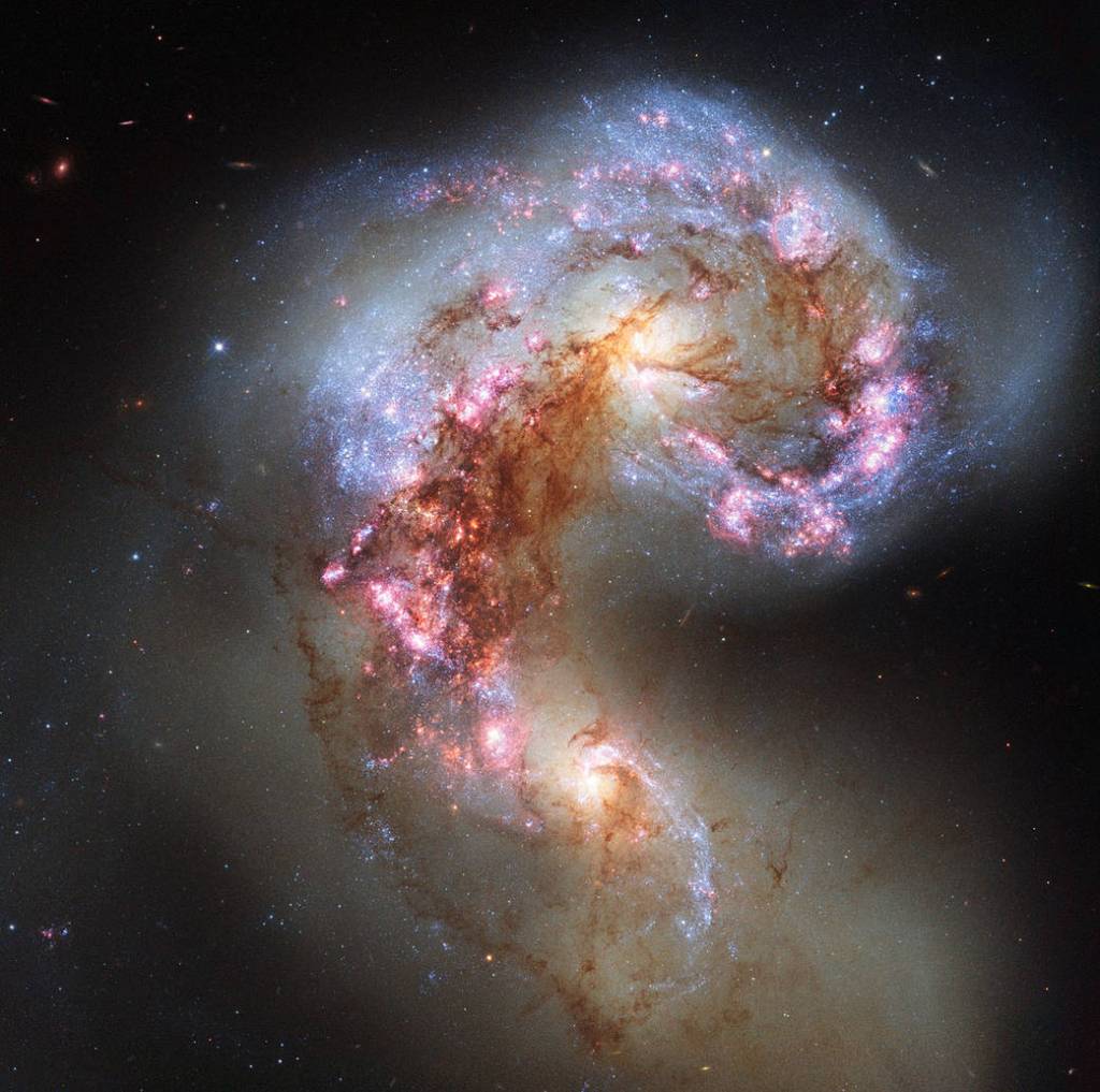 violent swirl of distorted galaxies with blue lanes of stars, pink star-formation areas and darker filaments of dust