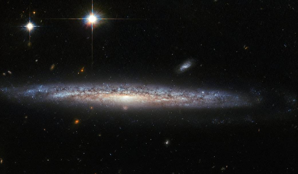 edge on galaxy with foreground stars and background spirals