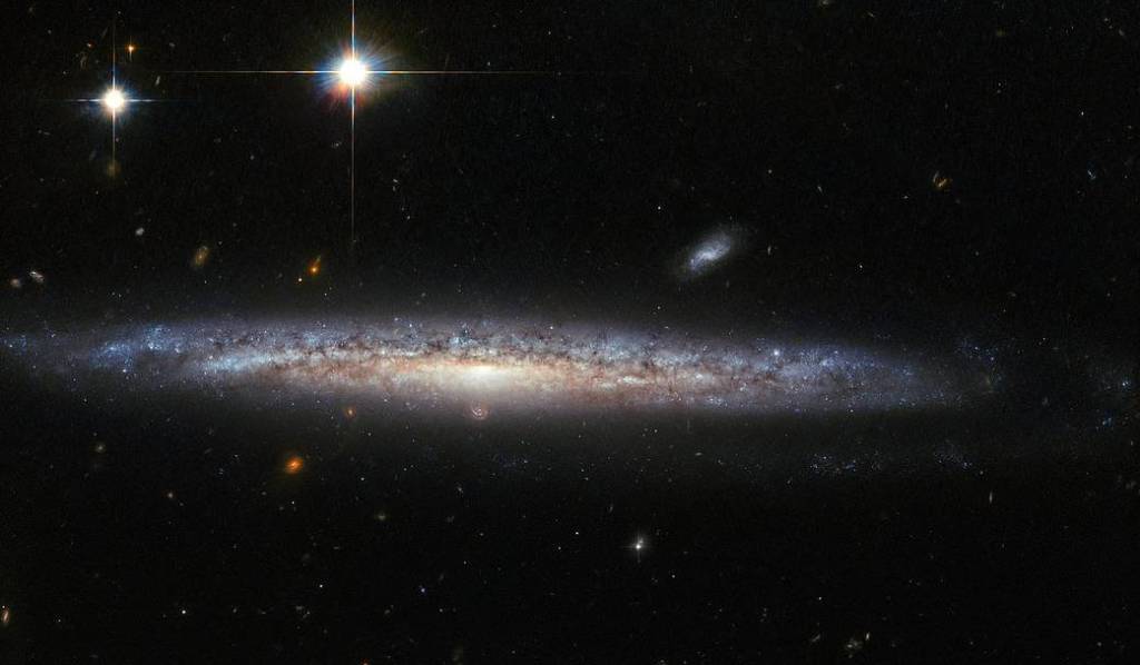 edge on galaxy with foreground stars and background spirals