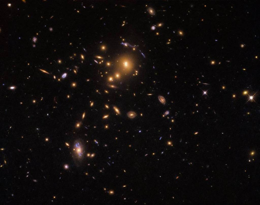 An upper left cluster of orange galaxies with a few blue streaks around them
