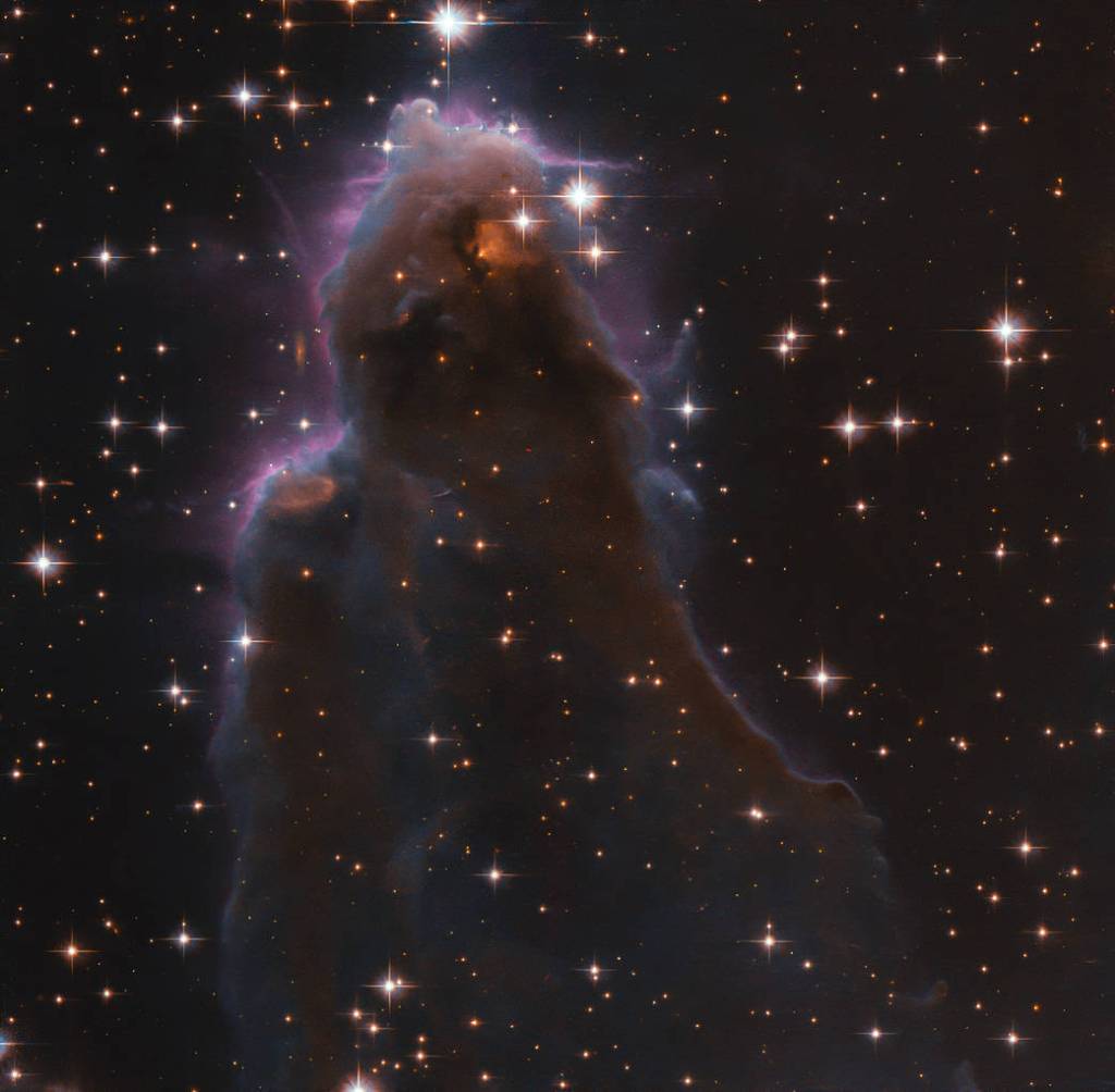 whisp-like, purple-hued view of star-forming region J025157.5+600606 against black backdrop of space, as seen by Hubble