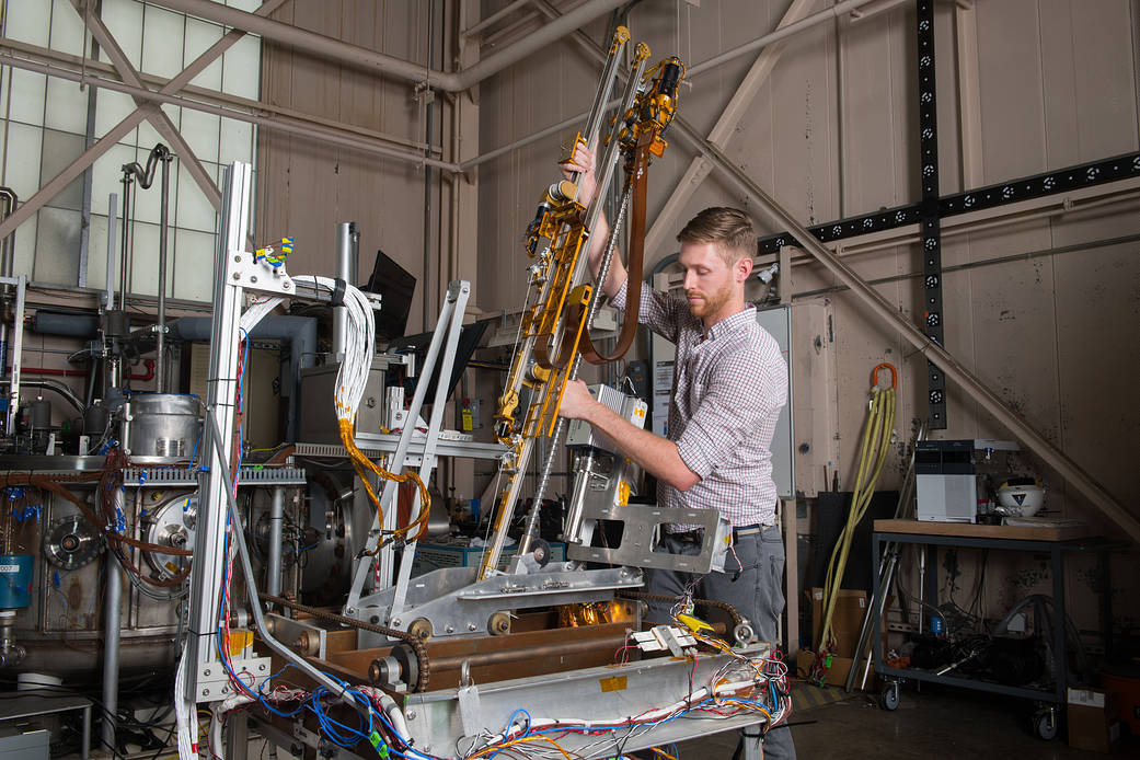 Honeybee Robotics Systems Engineer Zach Mank installs TRIDENT on a trolley for thermal vacuum chamber testing. Credits: NASA