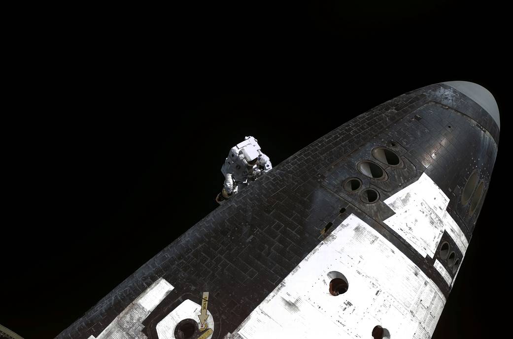 Steve Robinson nspects the underside of Space Shuttle Discovery