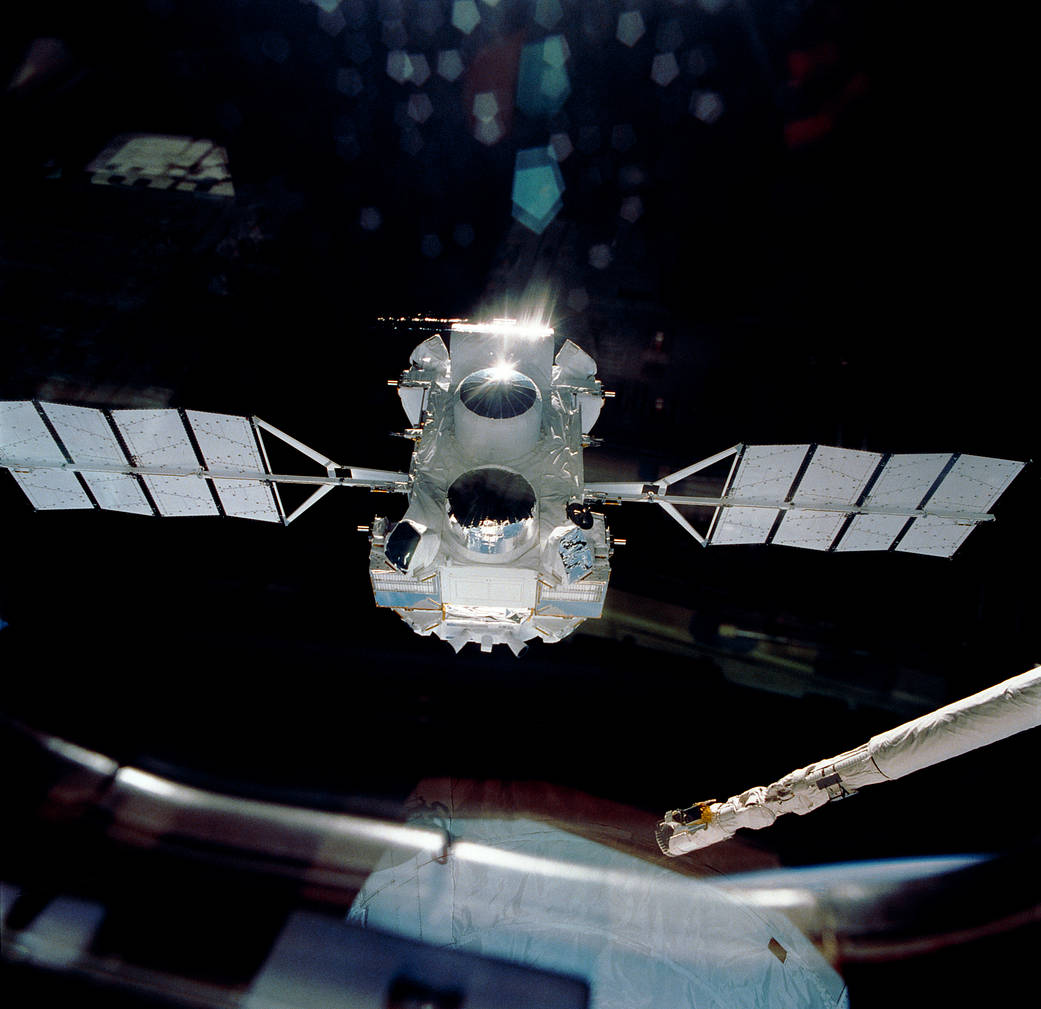 Observatory with solar arrays on either side drifts away from shuttle Atlantis into space