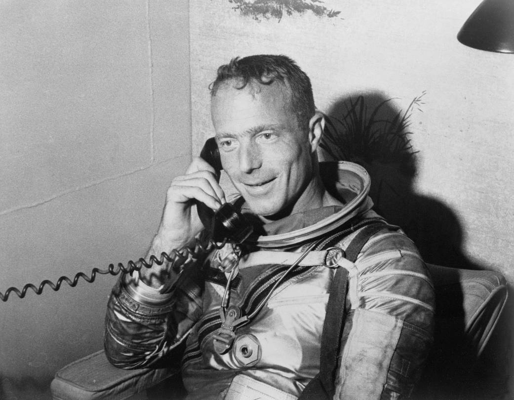 Scott Carpenter in spacesuit after mission splashdown speaks on telephone