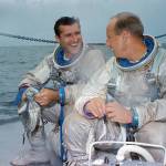 Two astronauts in spacesuits on deck of ship