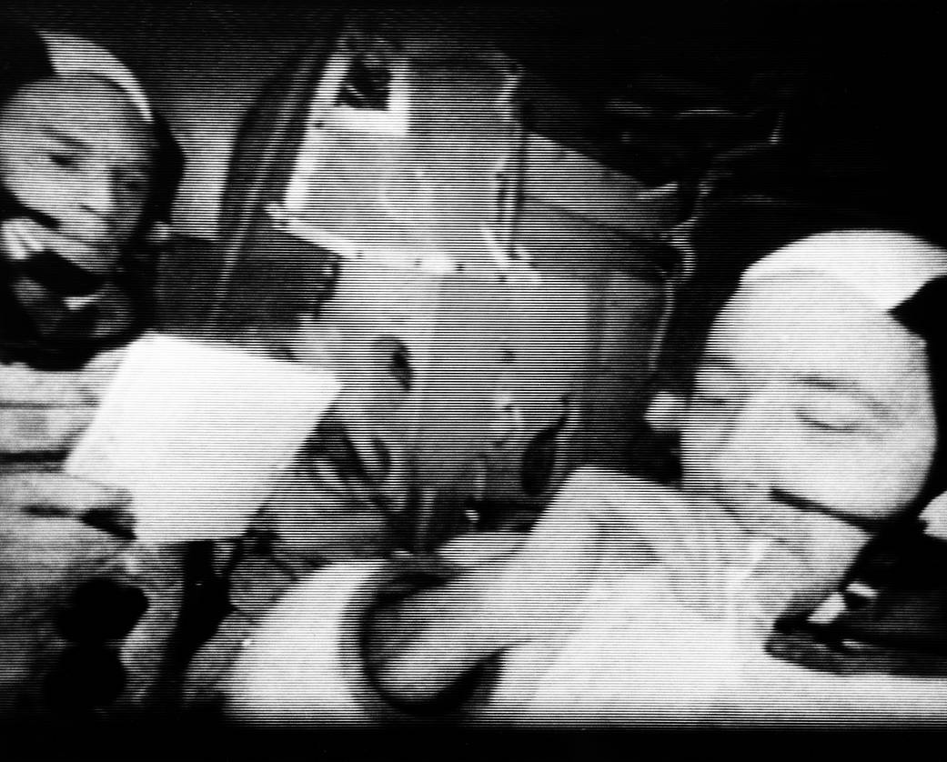 Photo from television transmission showing closeup of two astronauts inside capsule