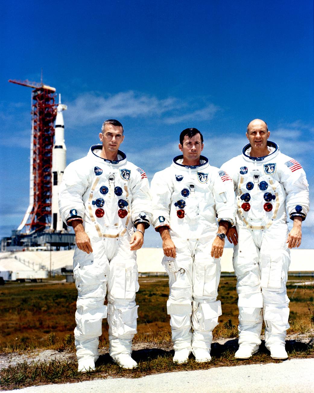 Apollo 10 crew portrait in spacesuits with rocket in background
