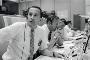Men with headsets at control desk in Mission Control
