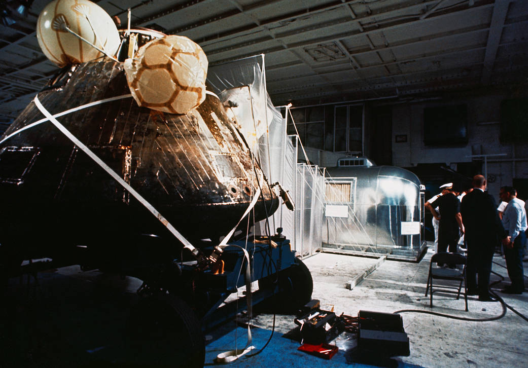 The Apollo 11 spacecraft Command Module (CM) and the Mobile Quarantine Facility (MQF) are photographed aboard the USS Hornet