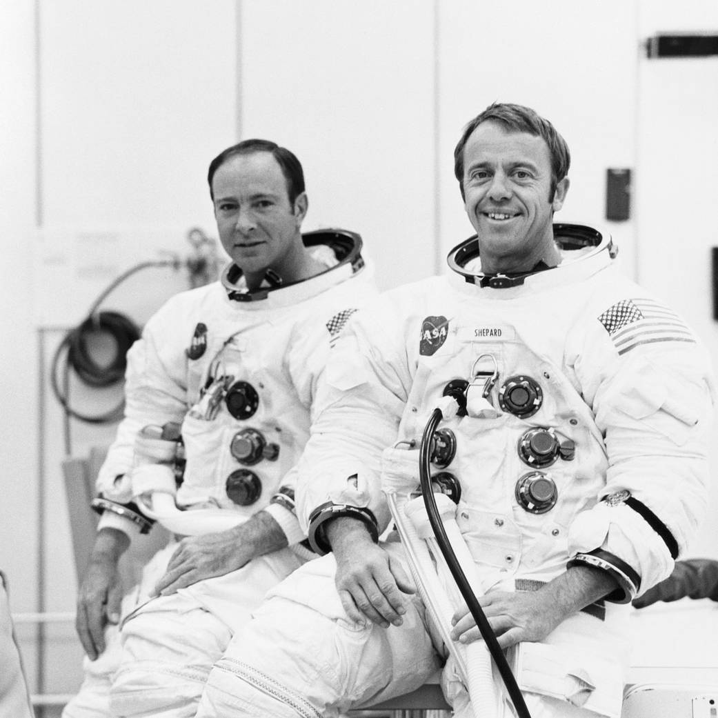 Astronauts Alan Shepard and Edgar Mitchell in spacesuits, helmets off, during training