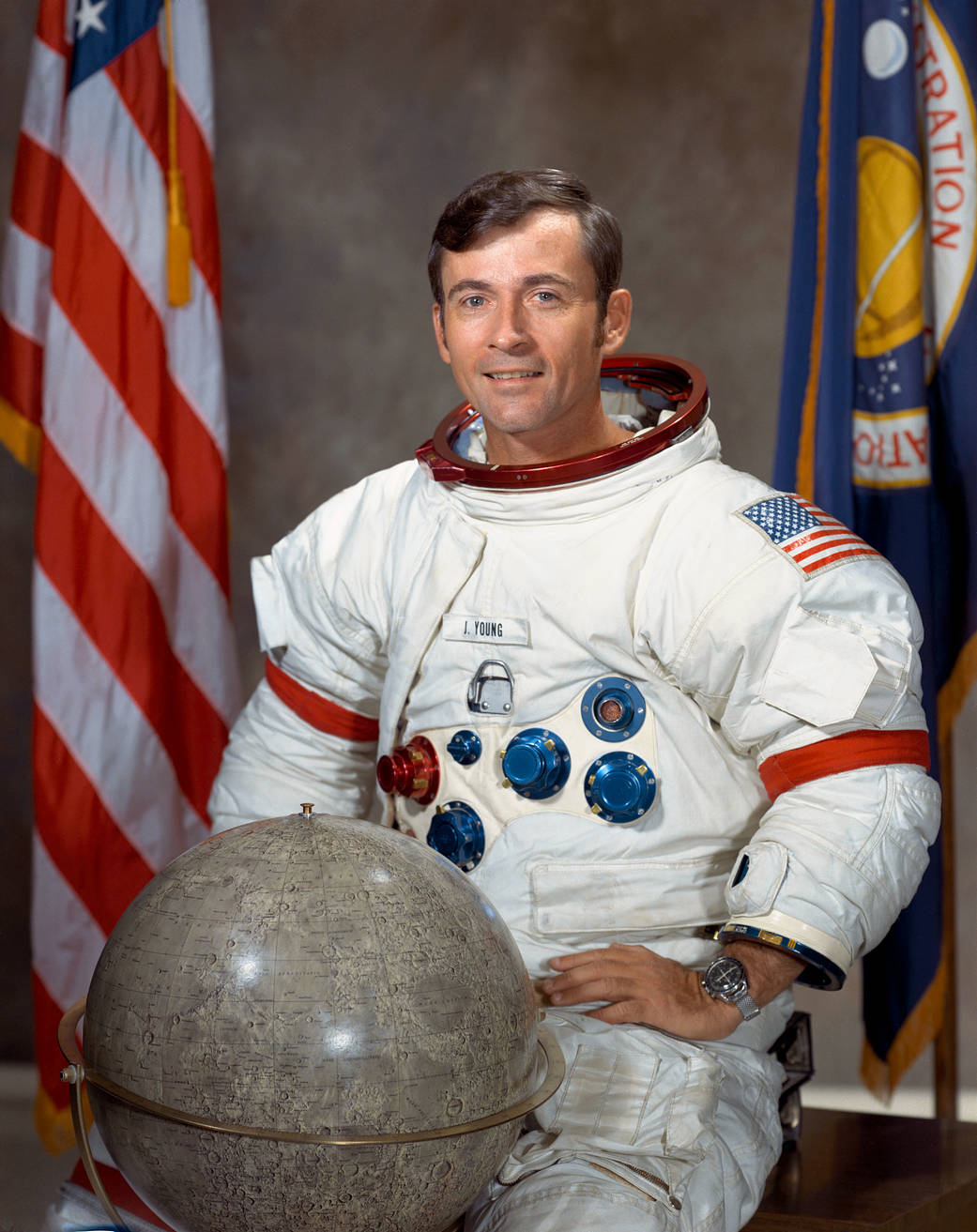 Official portrait of astronaut John Young with globe and American flag