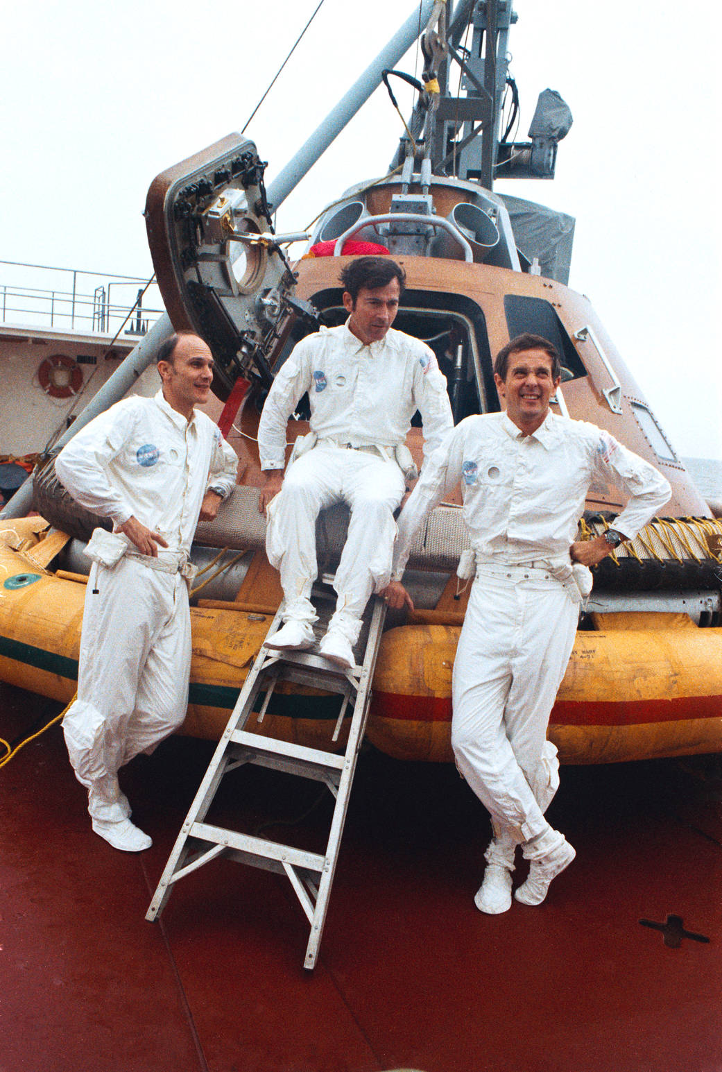 Three astronauts pose for photo with test model of spacecraft
